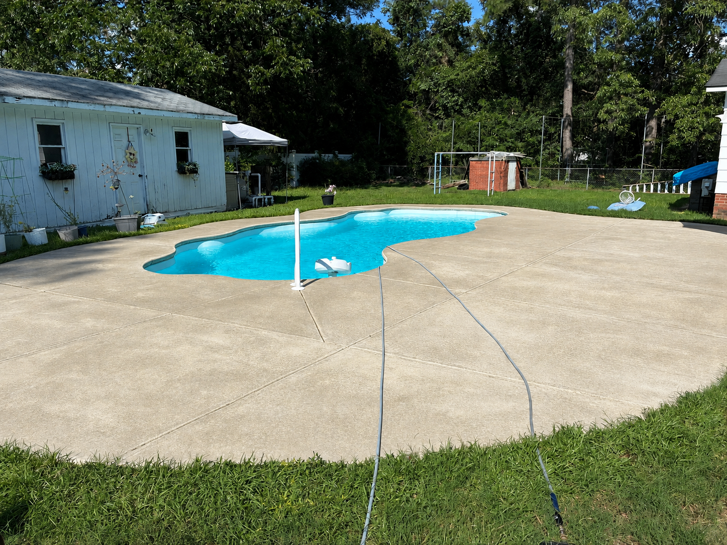 The same concrete pool deck after pressure washing, clean and bright