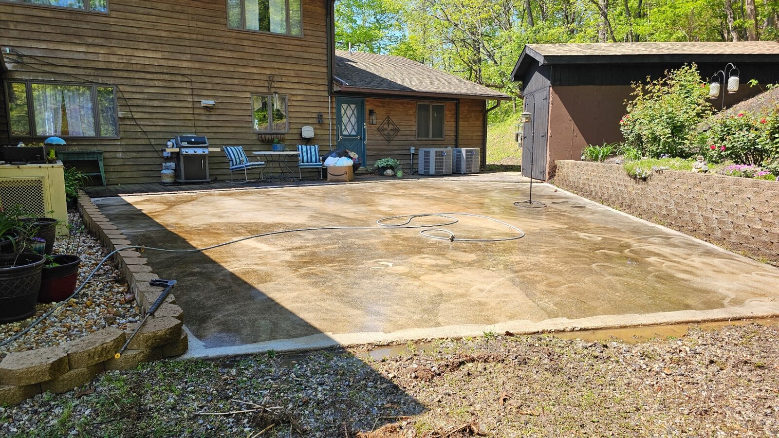 Concrete patio before pressure washing, covered in stains and organic buildup