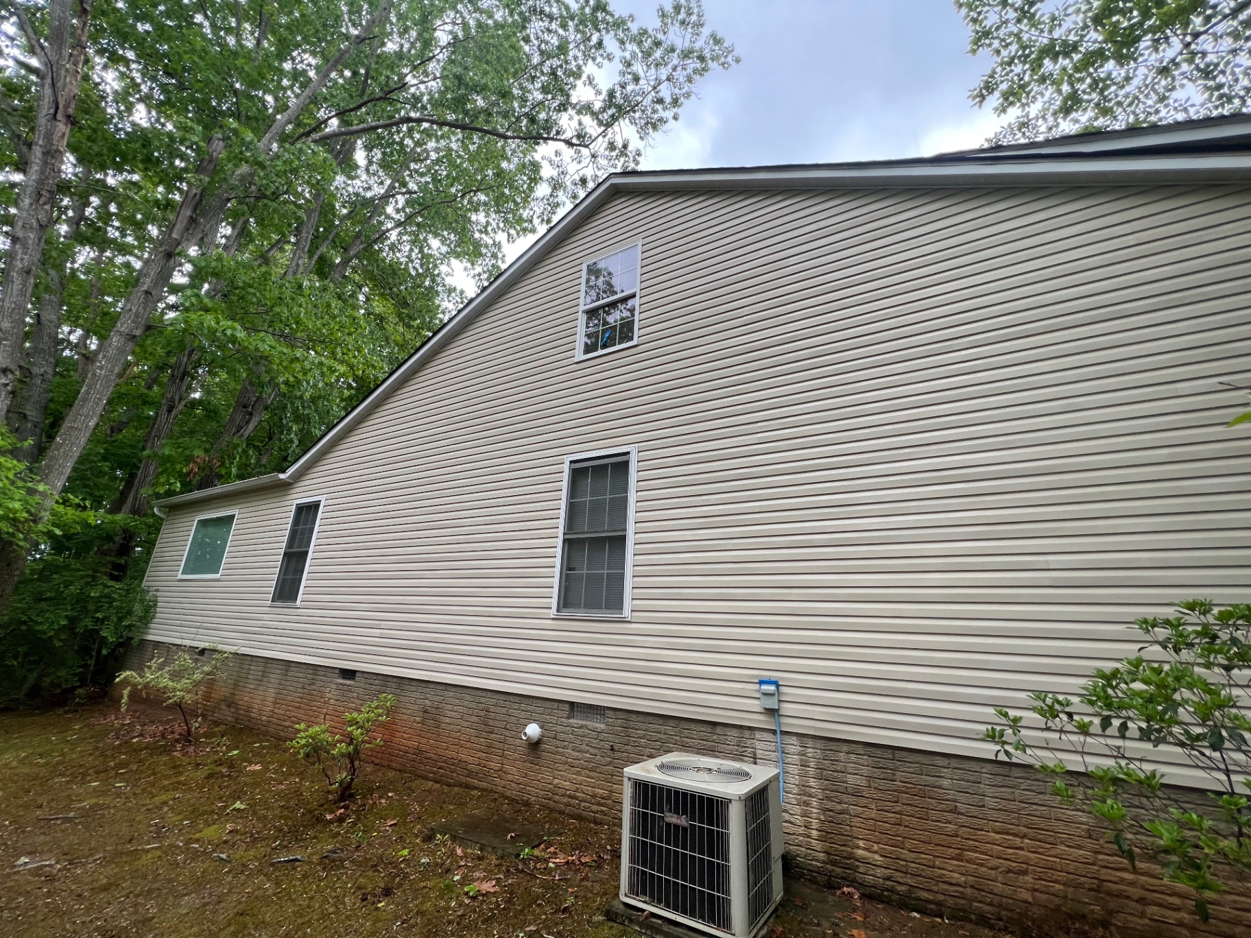 The same tan vinyl siding clean and bright after soft washing