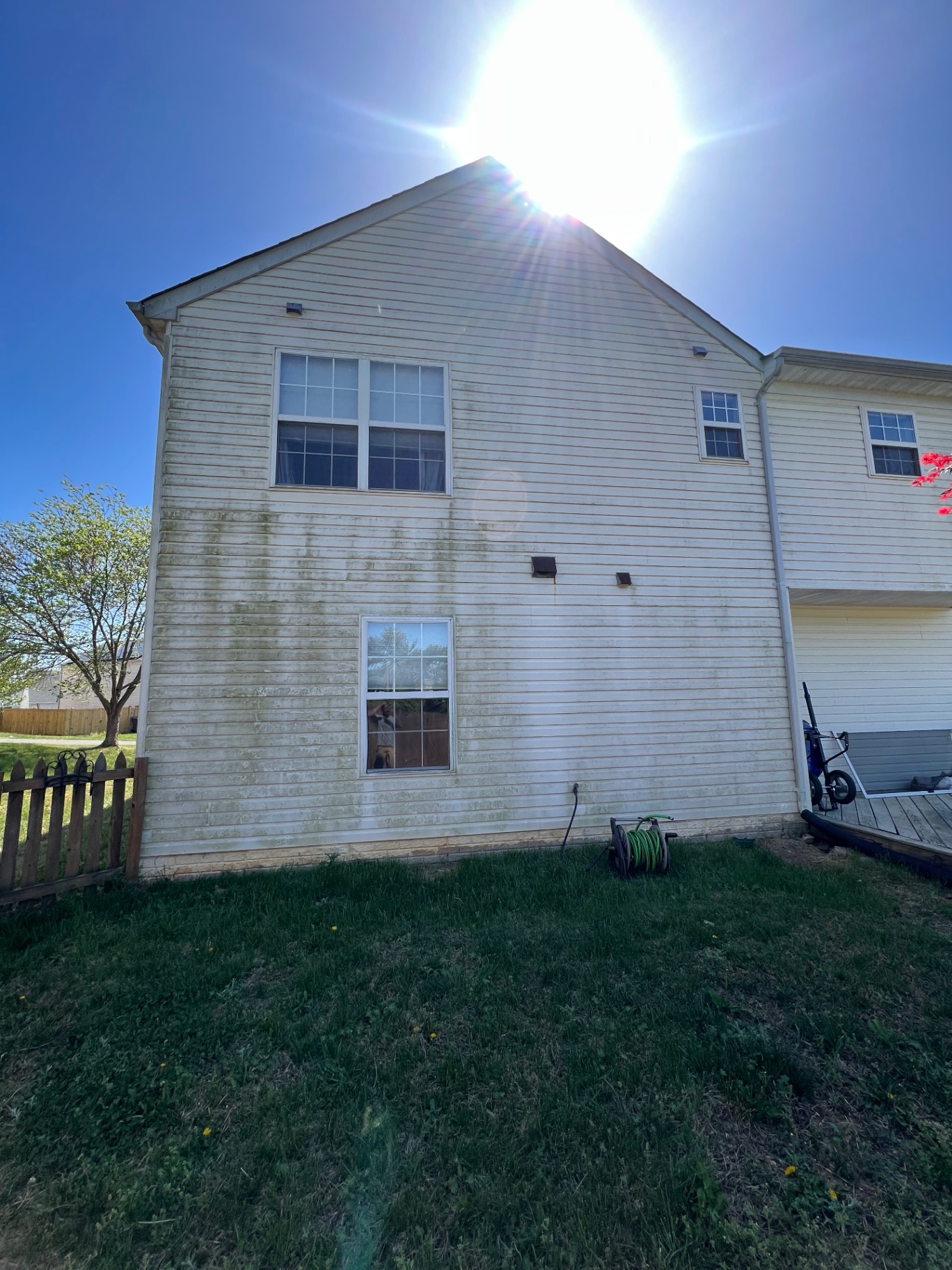Cream vinyl siding with heavy streaking and organic growth before soft washing